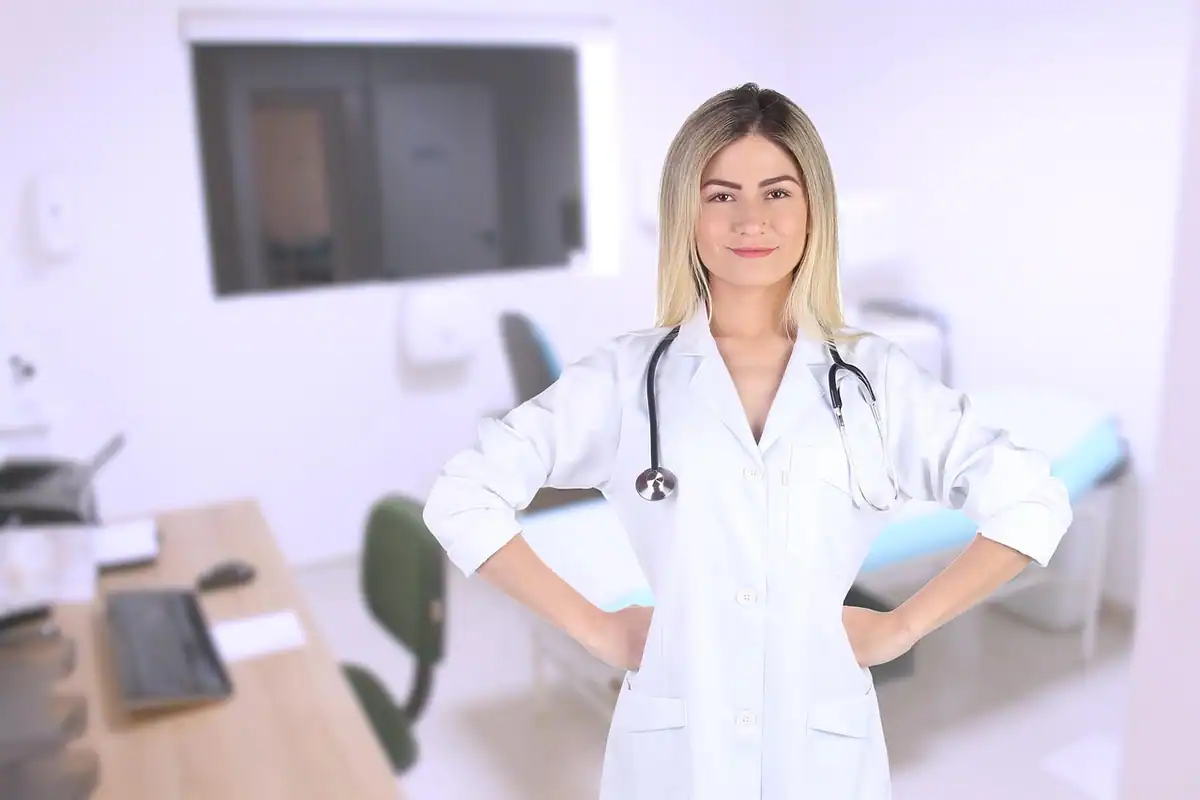 Medic de familie zâmbitor în halat alb, în picioare în cabinetul său