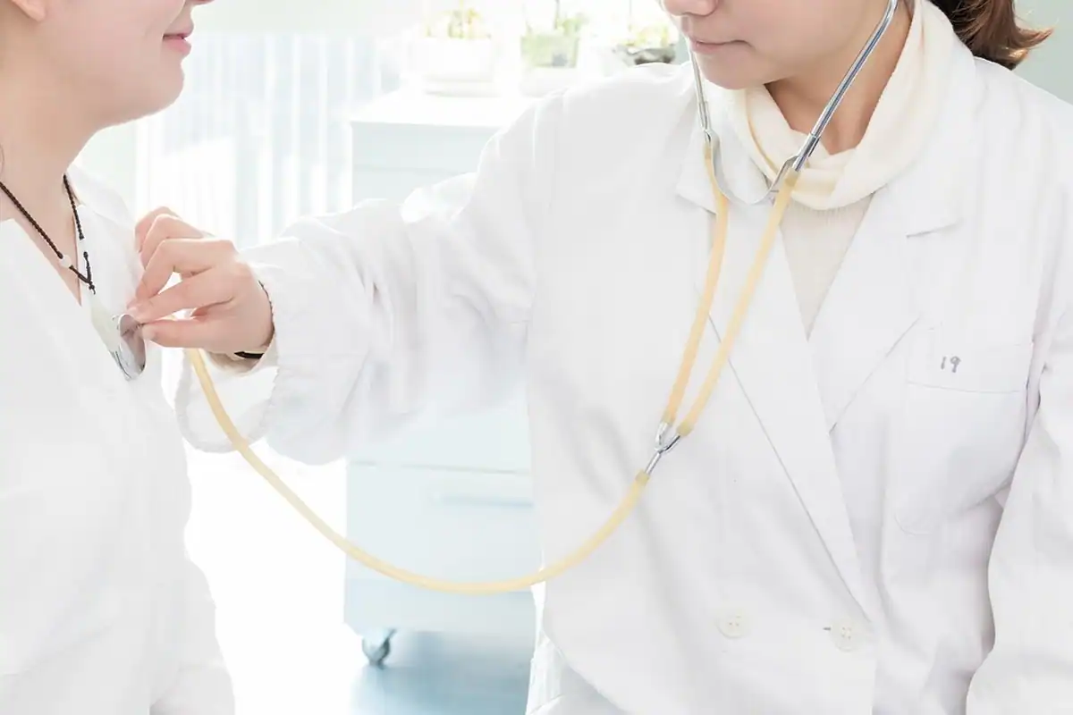 Asistentă cu stetoscop examinează un pacient într-un cabinet medical luminos