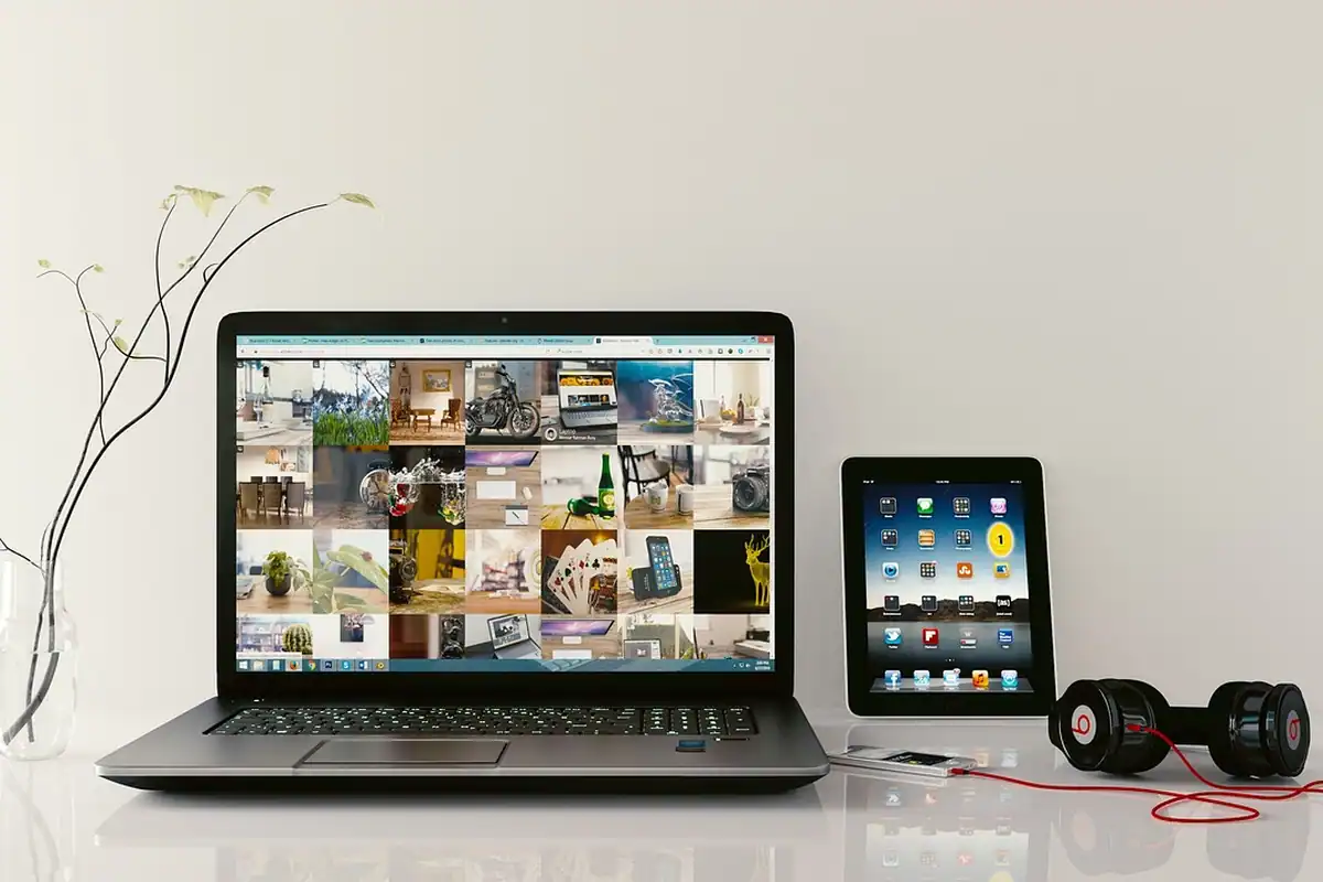 Laptop, tabletă și căști pe un birou, într-un spațiu de lucru digital