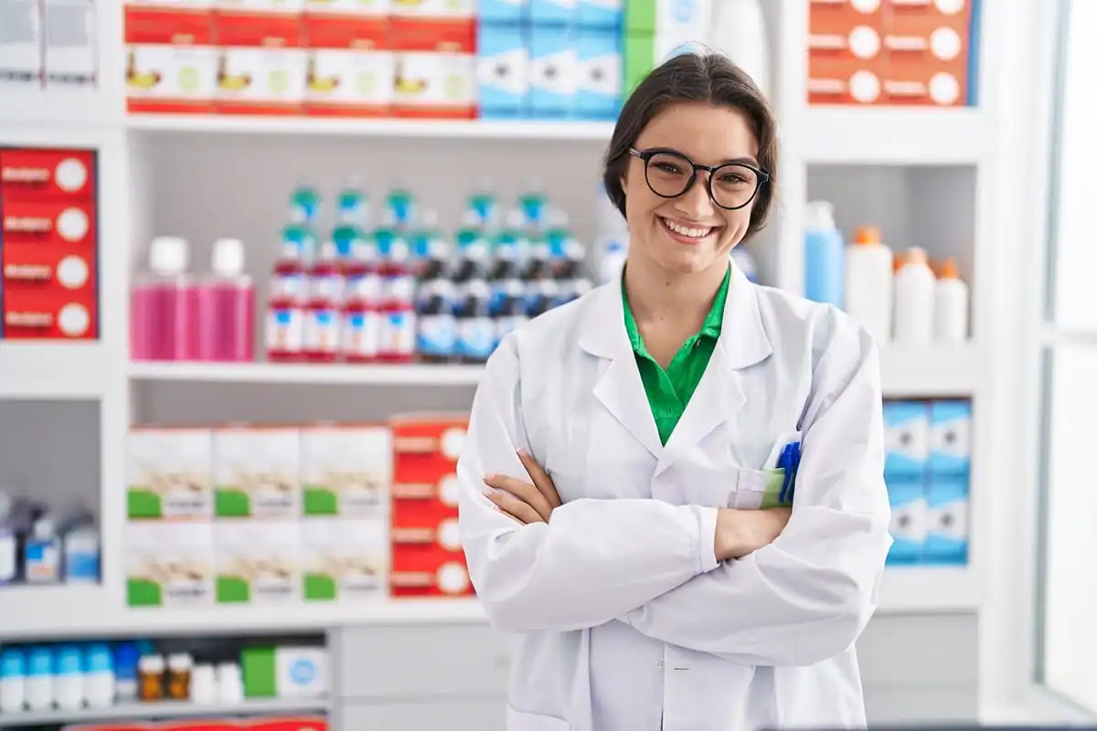 Farmacistă zâmbitoare în halat alb lângă rafturi pline cu medicamente
