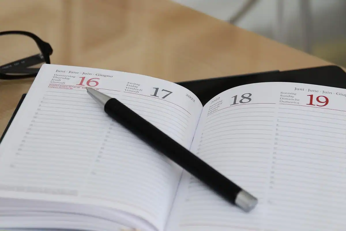 Agendă deschisă cu calendar și evenimente notate, folosită pentru planificare