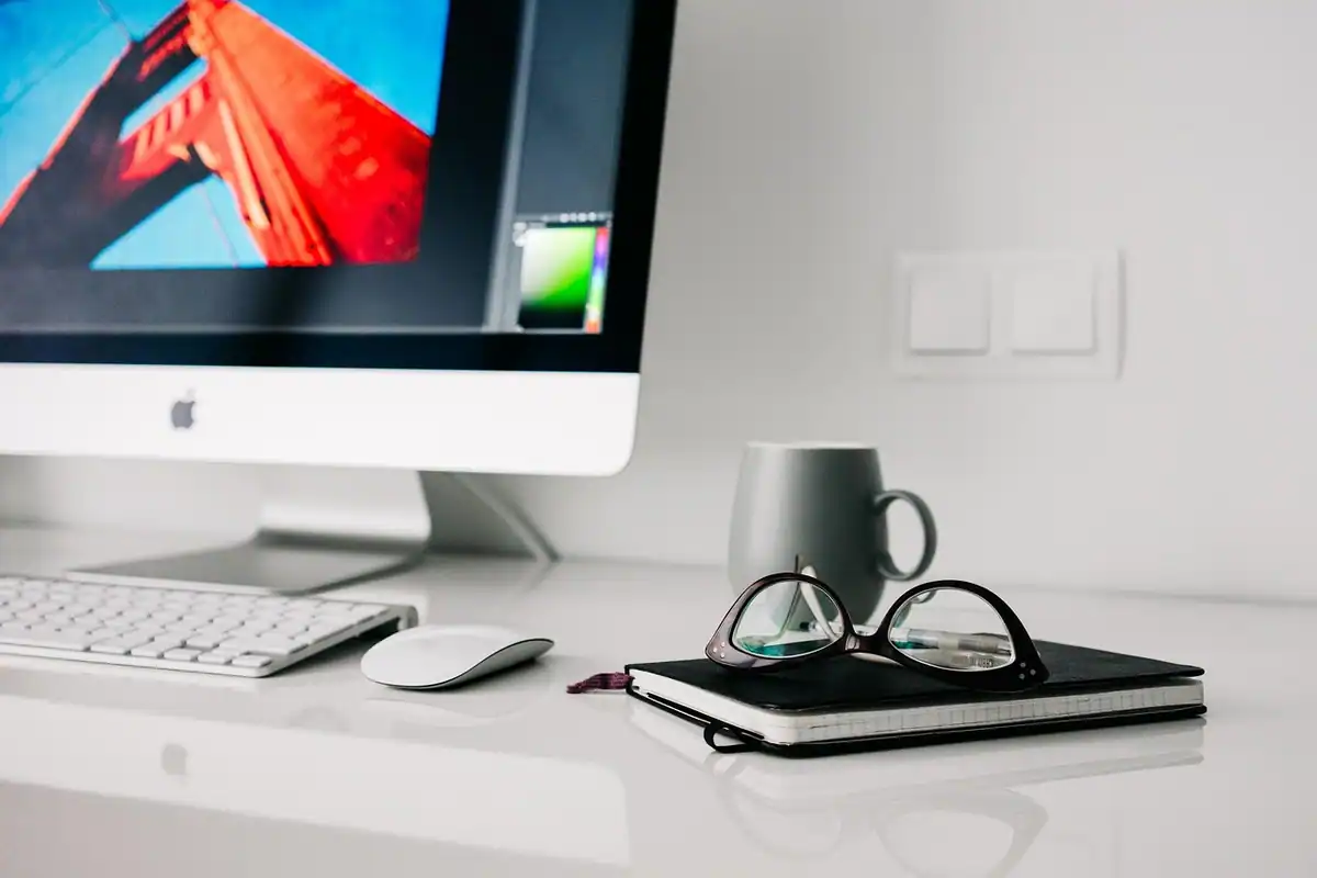 Spațiu de lucru de acasă cu desktop, caiet și ochelari pe o masă, în stil modern