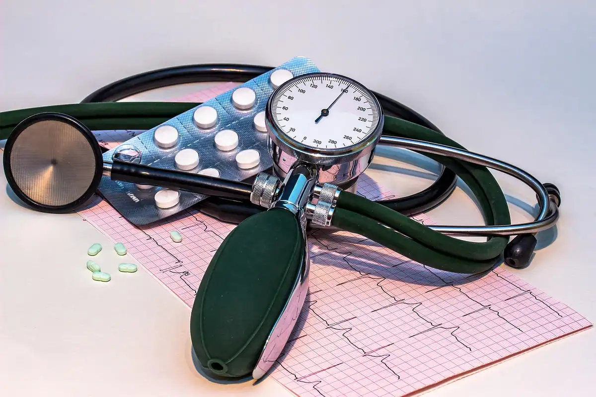 Tensiometru, stetoscop și pastile așezate pe o electrocardiogramă