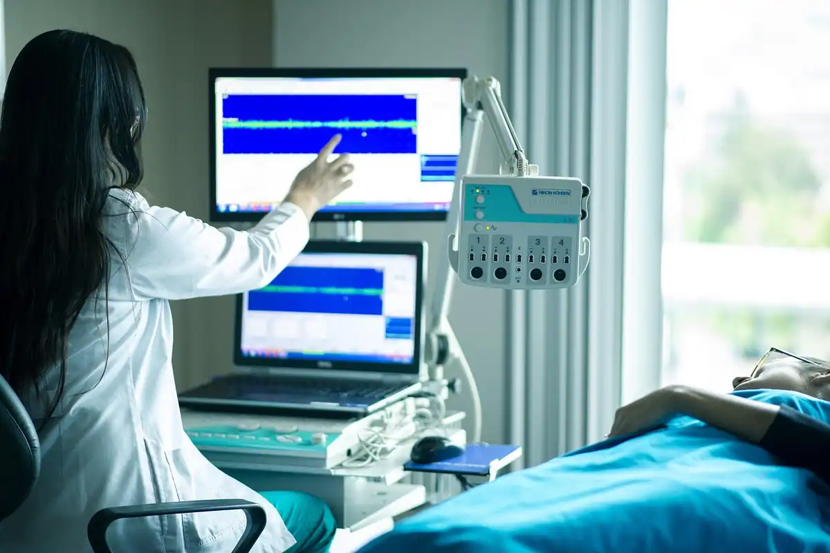 Medic urmărește monitoarele unui aparat de investigații lângă patul pacientului