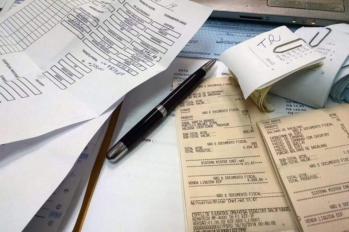 Bonuri fiscale, hârtii și un pix pe birou, pregătite pentru rambursare