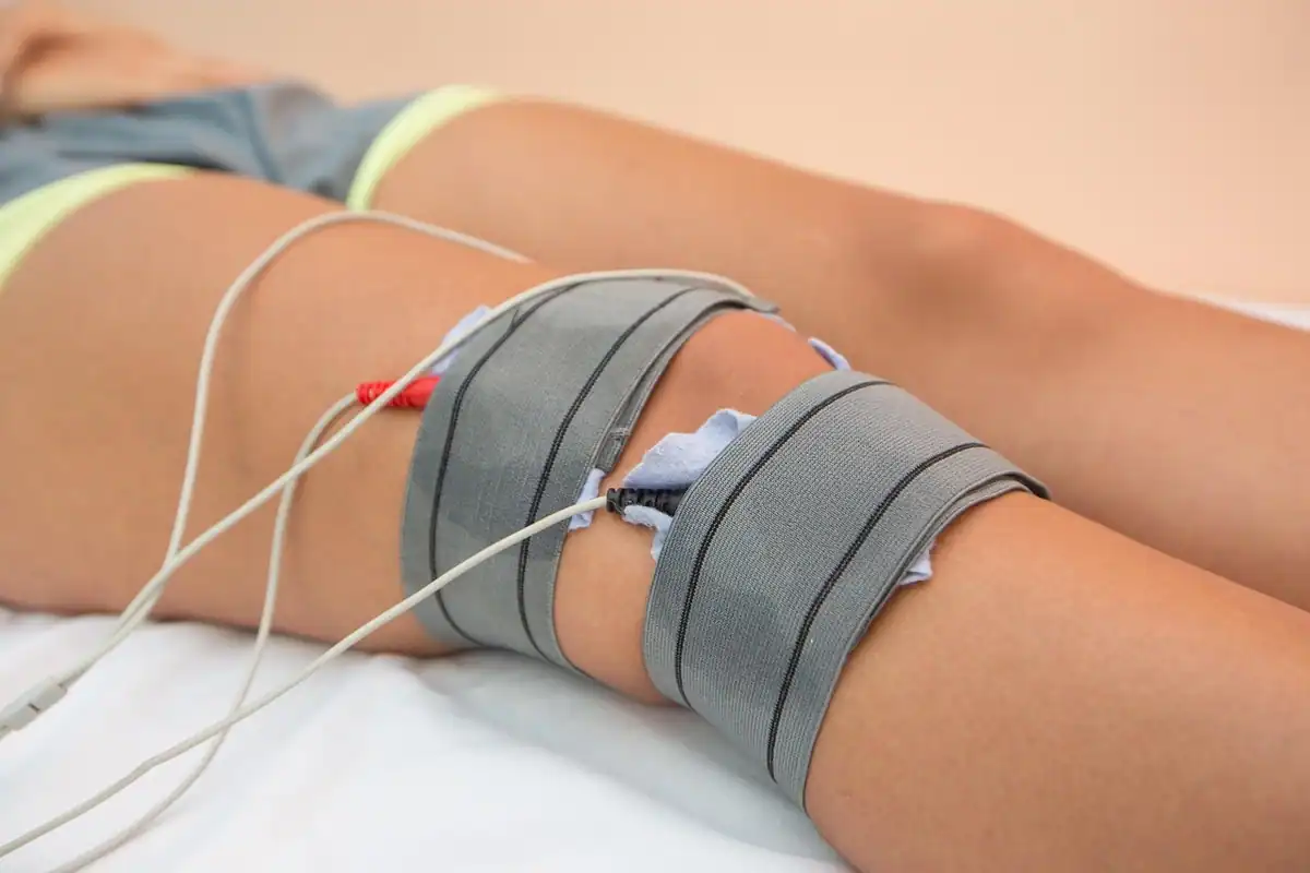 Electrozi de fizioterapie prinși pe piciorul unui pacient, în timpul tratamentului