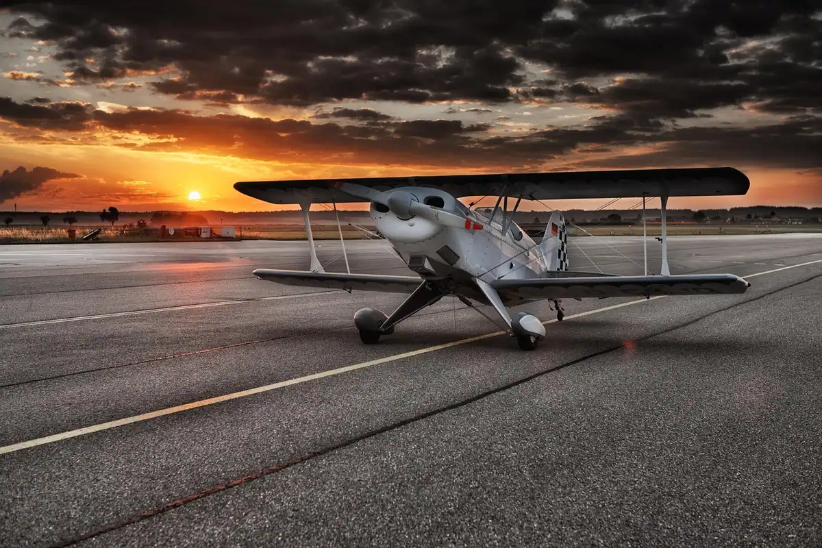 Avion vechi cu elice pe pista unui aeroport, în lumina apusului de soare