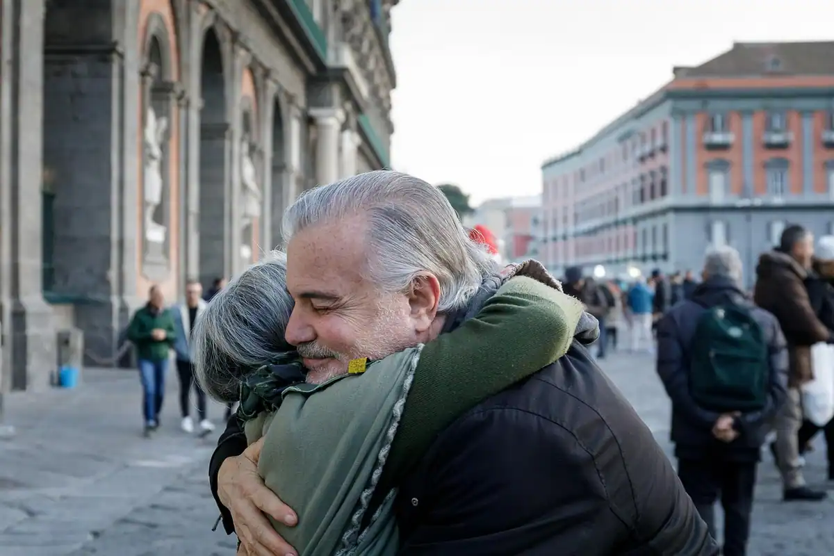 Doi oameni se îmbrățișează emoționați într-o piață a unui oraș, la reîntoarcere