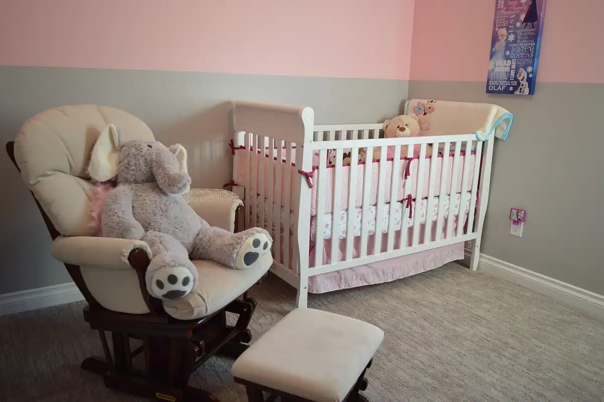 Cameră pentru bebeluș cu pătuț, scaun și mobilier, amenajată cu decor discret