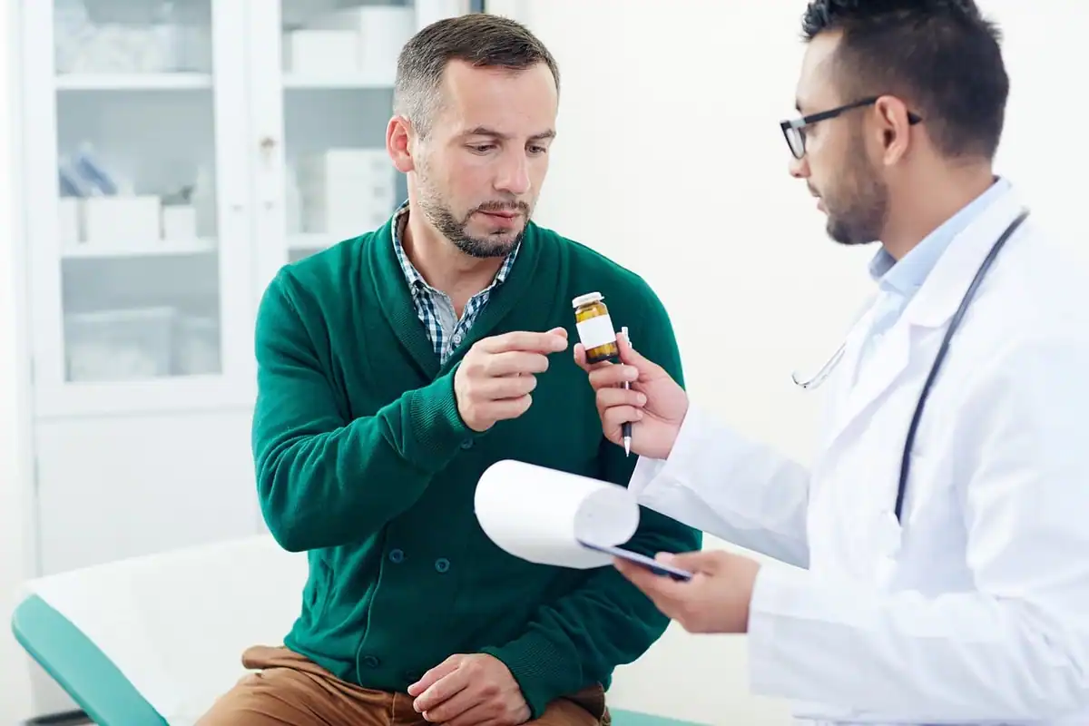 Pacient examinează un flacon cu medicament, alături de medicul său