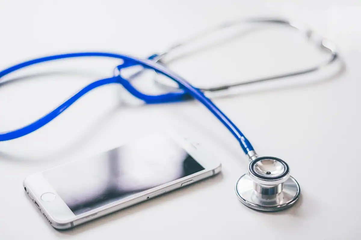 Stetoscop și telefon mobil așezate pe o masă, obiecte folosite într-un cabinet medical