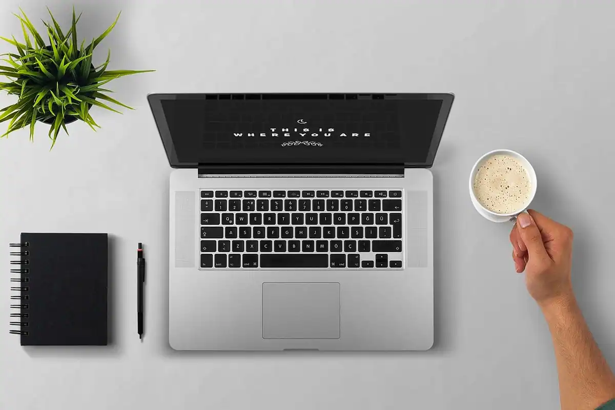 Laptop deschis și cană de cafea pe un birou, în timpul unei pauze de lucru