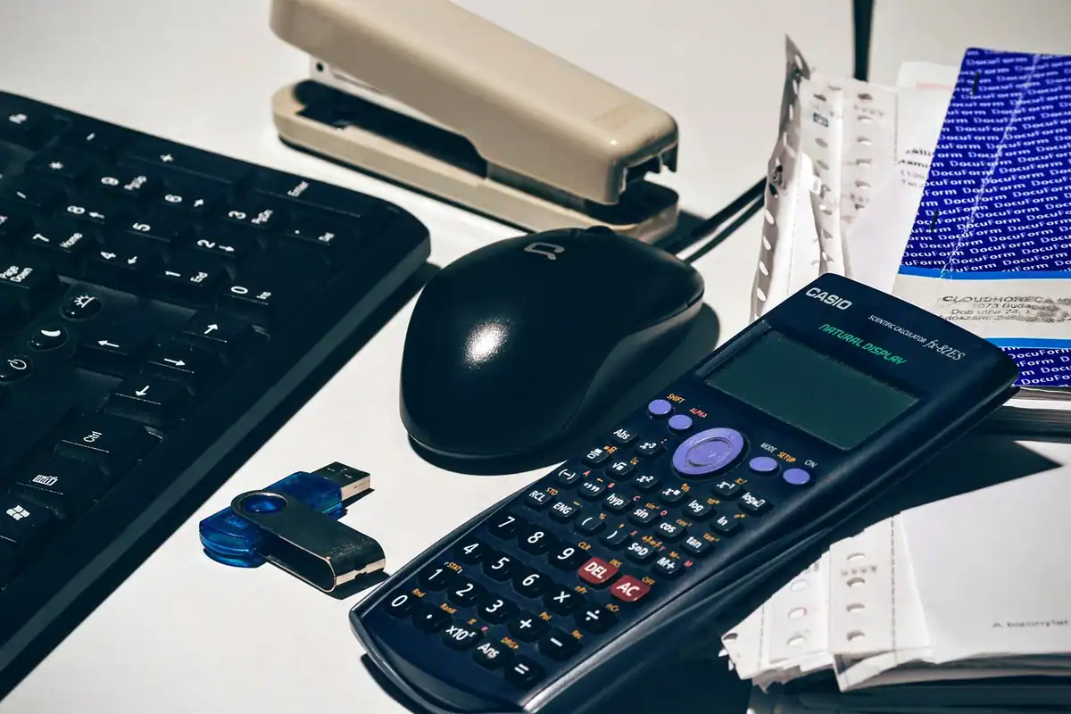 Birou de contabilitate cu calculator, tastatură, mouse, capsator și documente